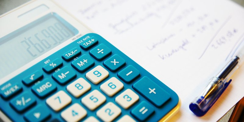 Taschenrechner, Stift und Zettel mit Berechnung