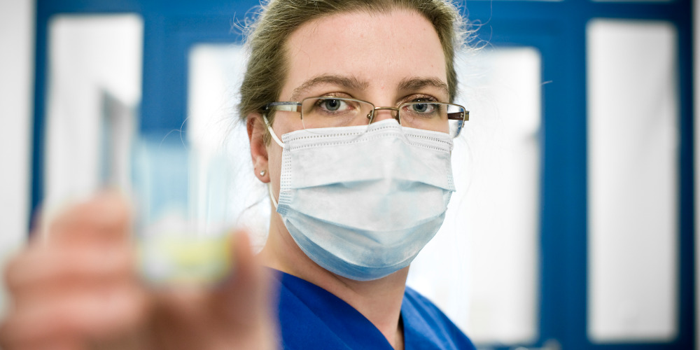 Frau mit Mundschutz im Krankenhaus hält Medizin in der Hand