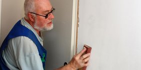 Älterer Mann beim Ausputzen einer Wand