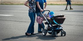 Familie Frau und Mann und Kleinkind im Kinderwagen