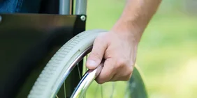 Hand am Rad von einem Rollstuhl