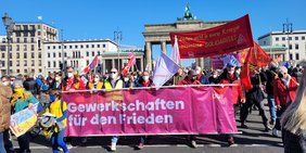 Foto: Demonstrationszug vor dem Brandenburger Tor, Gewerkschafter*innen tragen Banner: Gewerkschaften für den Frieden