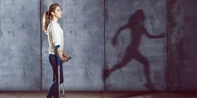 Junge Frau mit Krücken vor Schatten von laufener Frau