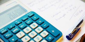Taschenrechner, Stift und Zettel mit Berechnung