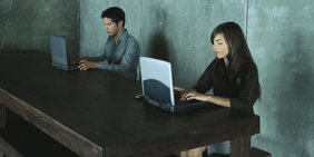 Symbolbild Digitalisierung Crowdworking Arbeit 4.0; Mann und Frau vor Laptops an großem Tisch