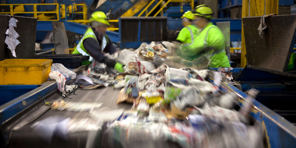 Beschäftigte am Fließband bei Müllsortierung
