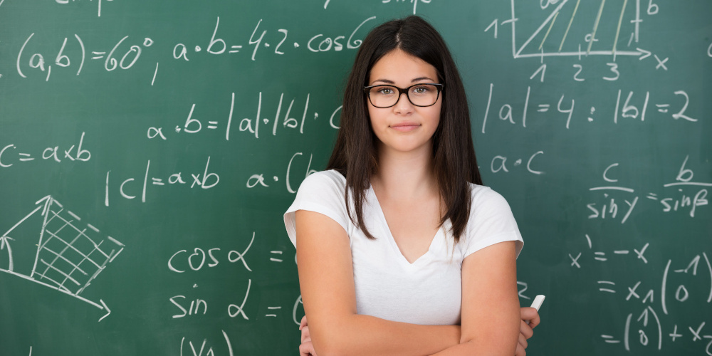 JUnge Frau steht vor Schultafel mit mathematischen Formeln