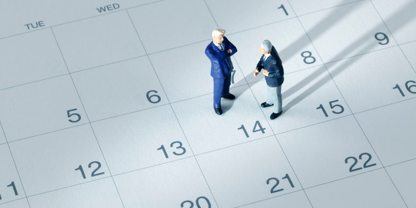 Zwei Miniaturfiguren im Anzug stehen auf einem Kalenderblatt