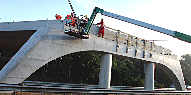 Bauarbeiter arbeiten mit Kran an Autobahnbrücke