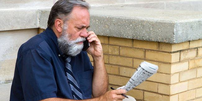 Älterer Mann mit Zeitung telefoniert