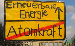 Schild vor dem Brandenburger Tor weist ein Transparent den Weg: Weg von der Atomkraft, hin zu erneuerbaren Energien.