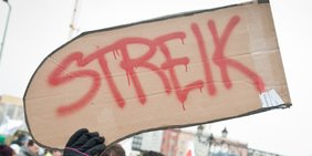 Ein hochgehaltenes Pappschild mit der Aufschrift: Streik.