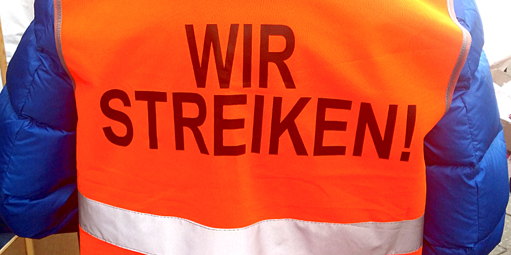 Rückenseite einer orangenen Warnweste mit der Aufschrift "Wir streiken"