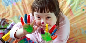 Kind mit Down-Syndrom und bemalten Händen