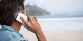 Nahaufnahme Mann am Strand mit Smartphone am Ohr