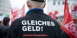 Von hinten fotografierter Mann, auf dessen Jacke "Gleiches Geld" steht. 