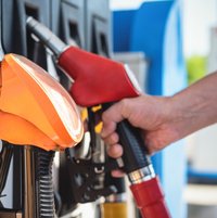 Der Mann hält eine Zapfpistole aus nächster Nähe an der Tankstelle