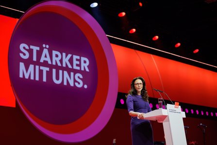 Yasmin Fahimi im violetten Kleid steht am Rednerpult, hinter ihr eine große Leinwand mit dem Slogan "STÄRKER MIT UNS" in rot und lila.