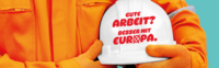Eine Person im orangefarbenen Arbeitsdress hält einen weißen Bauarbeiterhelm mit der Aufschrift "Gute Arbeit? Besser mit Europa"