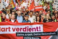 DGB-Vorsitzende Yasmin Fahimi steht mit weiteren Gewerkschaftsvertreter*innen hinter dem Transparent „Hart verdient!“; dahinter demonstriert eine dicht gedrängte Menschenmenge.