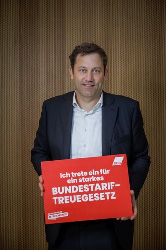 Foto von Lars Klingbeil, der ein rotes Schild in der Hand hält mit der Aufschrift "Ich trete ein für ein starkes Bundestariftreuegesetz"
