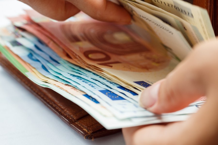 Nachaufnahme: Hände öffnen braunen Ledergeldbeutel voll mit Euro-Banknoten.