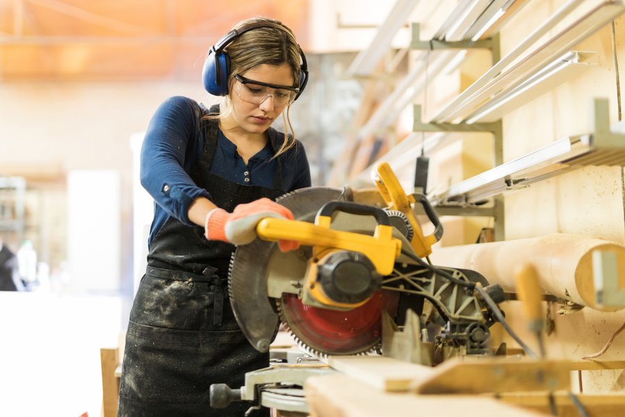 Tischlerin, die eine Kreissäge für ihre Arbeit in der Werkstatt verwendet.