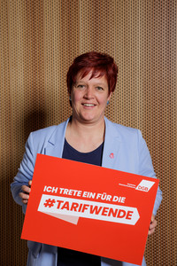 Portrait von Susanne Ferschl, gewerkschafts- und arbeitsmarktpolitische Sprecherin der Gruppe Die Linke im Bundestag, die ein Plakat hält mit der Aufschrift "Ich trete ein für die Tarifwende"