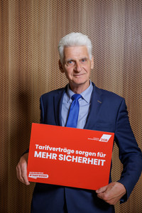 Rolf Schmachtenberg, der ein Plakat hält mit der Aufschrift "Tarifverträge sorgen für mehr Sicherheit"