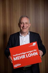Jürgen Kerner, der ein Plakat hält mit der Aufschrift "Tarifverträge sorgen für mehr Lohn"
