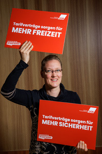 Romana Wittmer, die Plakate hält mit der Aufschrift "Tarifverträge sorgen für mehr Freizeit" und "Tarifverträge sorgen für mehr Sicherheit"