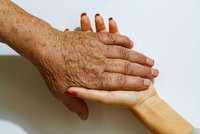 Eine ältere Person und eine junge halten Händchen.