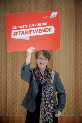 Foto von Nicole Mayer-Ahuja, Professorin für Soziologie an der Universität Göttingen, die ein DGB-Plakat in der Hand hält mit der Aufschrift "Ich trete ein für die  #Tarifwende"