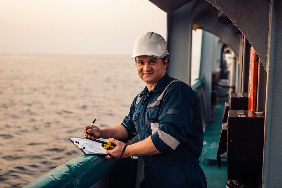 Deckoffizier an Deck eines Offshore-Schiffes oder -Schiffes, der persönliche Schutzausrüstung trägt. Er füllt Checkliste. Papierkram auf See