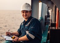 Deckoffizier an Deck eines Offshore-Schiffes oder -Schiffes, der persönliche Schutzausrüstung trägt. Er füllt Checkliste. Papierkram auf See