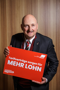 Bernd Rützel, der ein Plakat hält mit der Aufschrift "Tarifverträge sorgen für mehr Lohn"