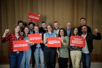 Gruppenbild von 13 Mitgliedern des Bundestage von der Partei Die Linke. Sie halten verschiedene rote Bilder mit den Aufschriften "Tarifverträge sorgen für mehr Lohn, mehr Sicherheit, mehr Freizeit", "Eintreten für die #Tarifwende" und "Ich trete ein für ein starkes Bundestariftreuegesetz". Damit zeigen sie ihre Unterstützung der #Tarifwende-Kampagne des DGB. 