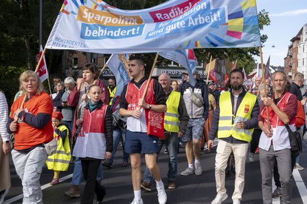 Demonstrierende ziehen mit ver.di-Fahnen und einem Banner für Inklusion und gute Arbeit durch Kiel.