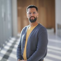 Portraitfoto von Hedi, Betriebsrat von Amazon, der ernst in die Kamera schaut.