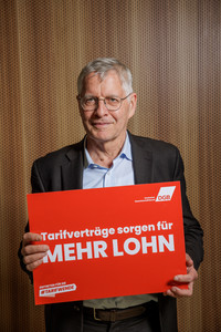 Gerhard Bosch, der ein Plakat hält mit der Aufschrift "Tarifverträge sorgen für mehr Lohn"