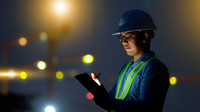 Ingenieur benutzt nachts ein digitales Tablet auf einer Baustelle. 