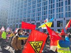 Demonstrationszug von der Seite, es sind Gewerkschaftsfahnen und Banner sowie Ukraine-Flaggen und Demoschilder zu sehen