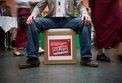 Mann sitzt auf Kiste mit dem Logo der Kampagne Deutschland braucht den Mindestlohn.