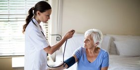 Pflegerin misst Blutdruck bei älterer Frau