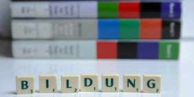 Scrabble-Buchstaben "Weiterbildung" vor Büchern aufgestellt